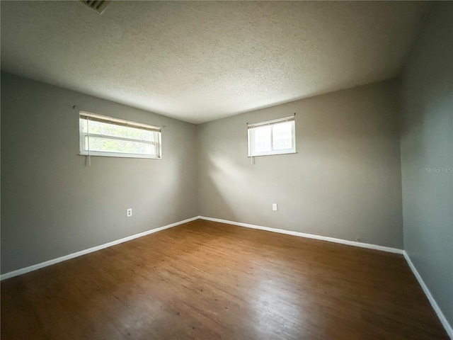 spare room with a wealth of natural light, hardwood / wood-style floors, and a textured ceiling