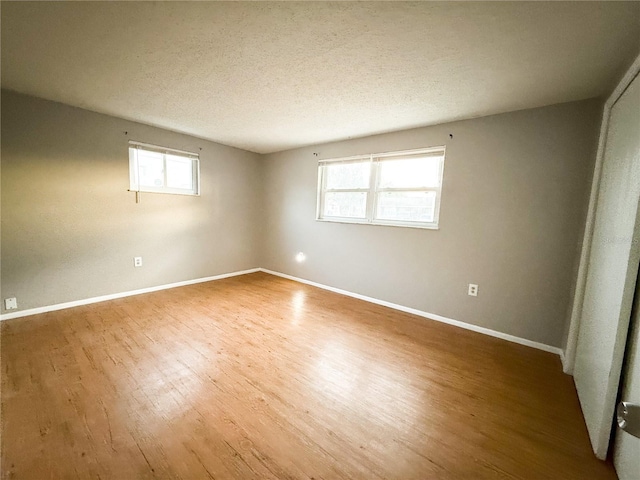 6417 Sutherland Ave, New Port Richey, FL 34653 - empty room featuring wood finished floors, healthy amount of natural light, baseboards, and a textured ceiling