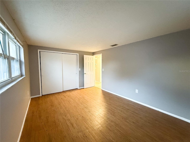 unfurnished bedroom with a closet, a textured ceiling, and light hardwood / wood-style floors