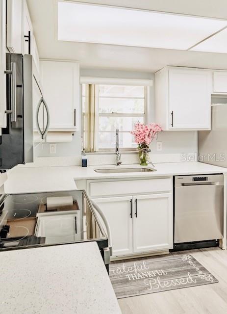 kitchen featuring white cabinetry, sink, light hardwood / wood-style flooring, and stainless steel appliances