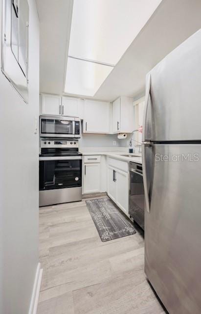 kitchen featuring white cabinetry, stainless steel appliances, sink, and light wood-type flooring