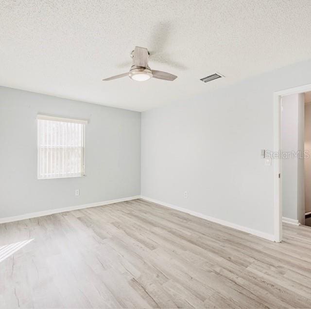 empty room featuring ceiling fan, a textured ceiling, and light wood-type flooring