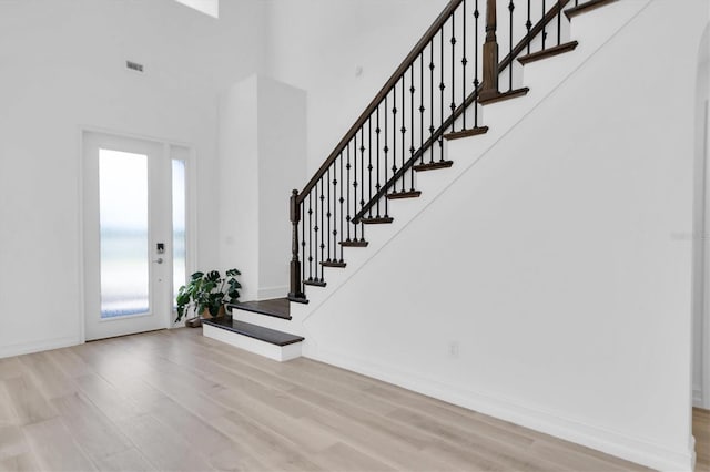 foyer entrance with a towering ceiling and light wood-type flooring