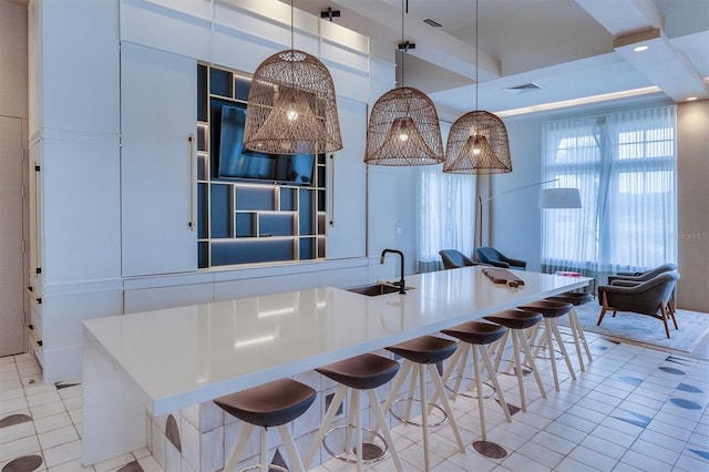 kitchen with pendant lighting, a kitchen breakfast bar, light tile patterned floors, and sink