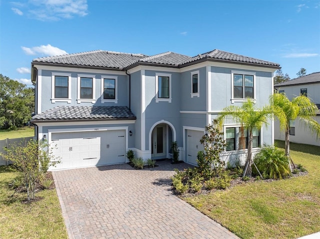 mediterranean / spanish house featuring a garage and a front lawn