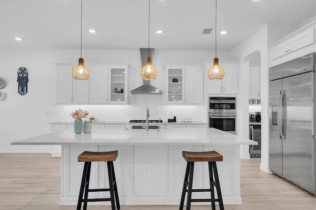 kitchen featuring wine cooler, a kitchen island with sink, hanging light fixtures, and appliances with stainless steel finishes