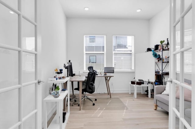 office with light hardwood / wood-style floors and french doors