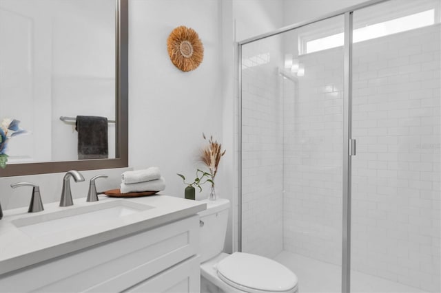 bathroom featuring vanity, a shower with shower door, and toilet