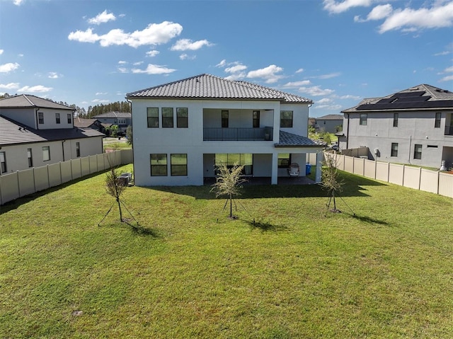 back of property featuring a patio area, a balcony, and a yard