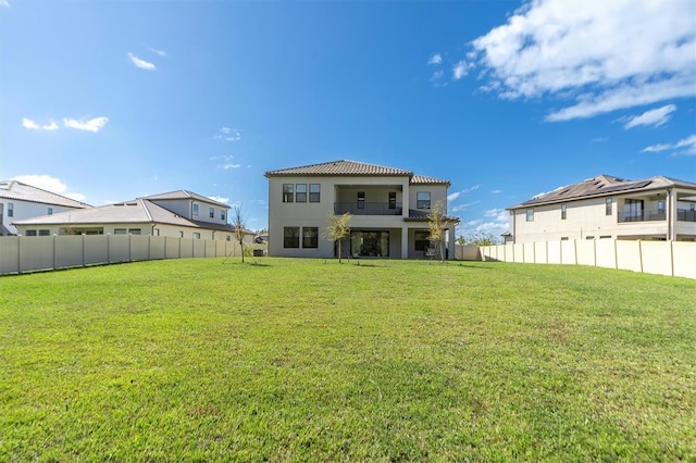 back of property with a yard and a balcony