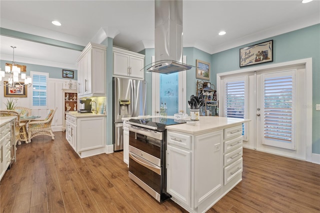 kitchen with pendant lighting, appliances with stainless steel finishes, a center island, island range hood, and white cabinets