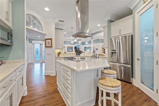 kitchen featuring crown molding, a breakfast bar area, appliances with stainless steel finishes, a kitchen island with sink, and island range hood