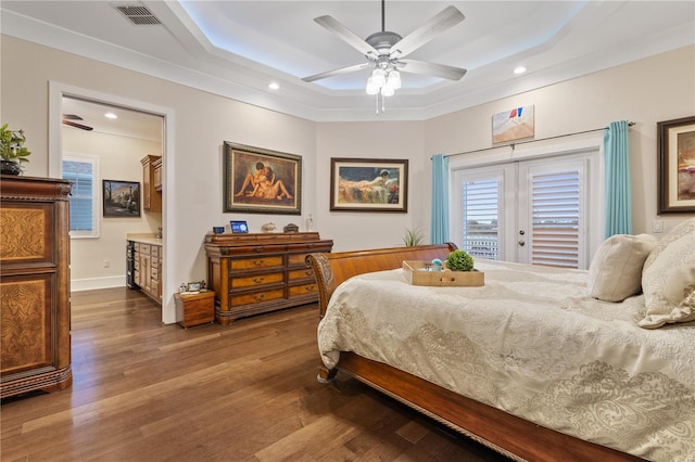 bedroom featuring hardwood / wood-style flooring, access to outside, a raised ceiling, and ceiling fan