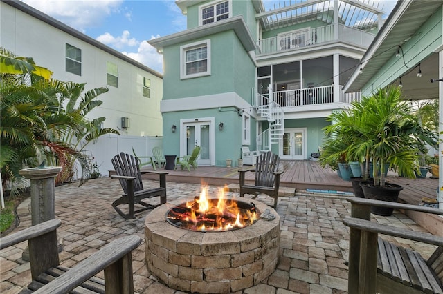 view of patio / terrace featuring a fire pit, a sunroom, french doors, and a deck