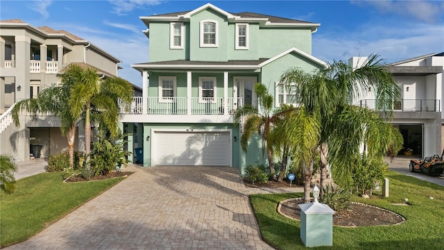 raised beach house with a garage, a balcony, and a front lawn