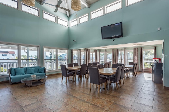 interior space with ceiling fan, a towering ceiling, and beamed ceiling