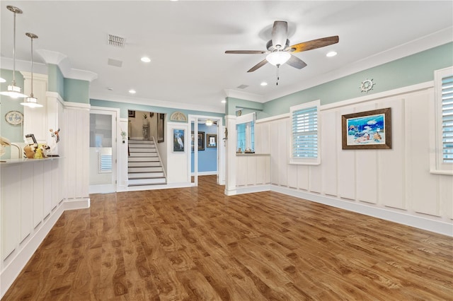 unfurnished living room with crown molding, wood-type flooring, and ceiling fan