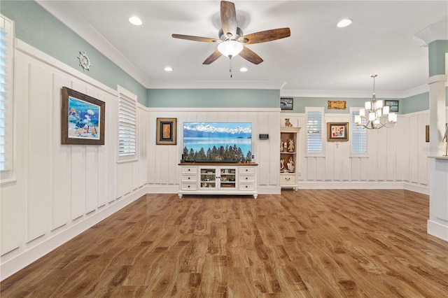 unfurnished living room with crown molding, ceiling fan with notable chandelier, and hardwood / wood-style floors