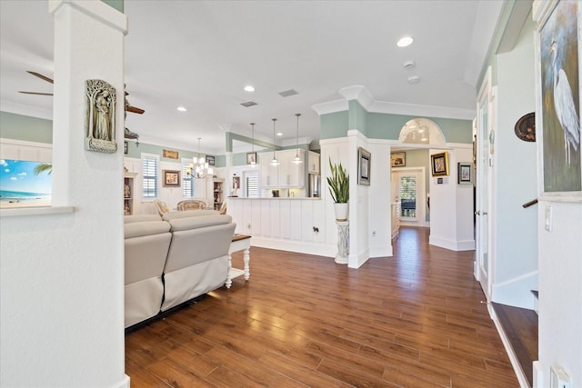 living room featuring crown molding, dark wood-type flooring, and ceiling fan with notable chandelier