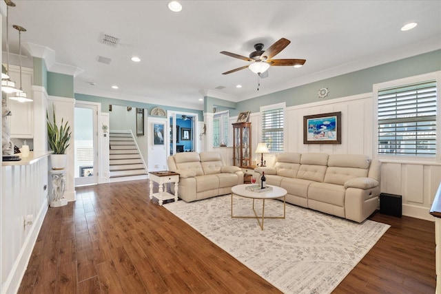 living room featuring dark wood-type flooring, ornamental molding, and ceiling fan