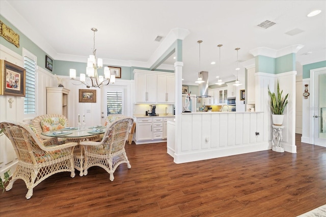 dining space with dark hardwood / wood-style flooring, crown molding, and an inviting chandelier