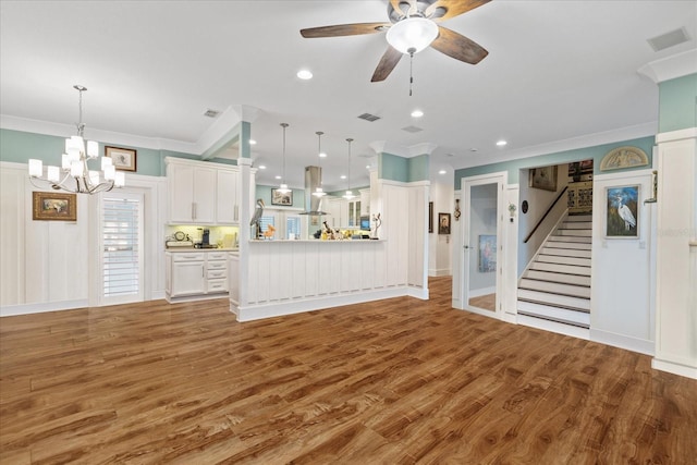 unfurnished living room featuring ornamental molding, wood-type flooring, and ceiling fan with notable chandelier