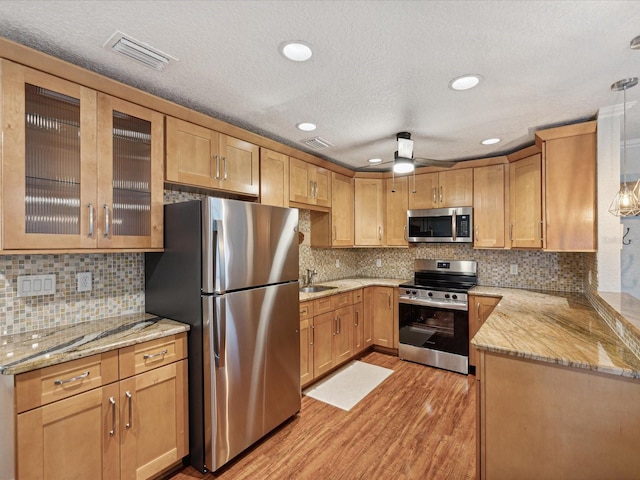 kitchen featuring light hardwood / wood-style floors, a textured ceiling, tasteful backsplash, ceiling fan, and appliances with stainless steel finishes