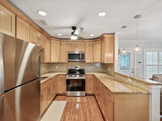 kitchen featuring light hardwood / wood-style floors, kitchen peninsula, ornamental molding, pendant lighting, and appliances with stainless steel finishes