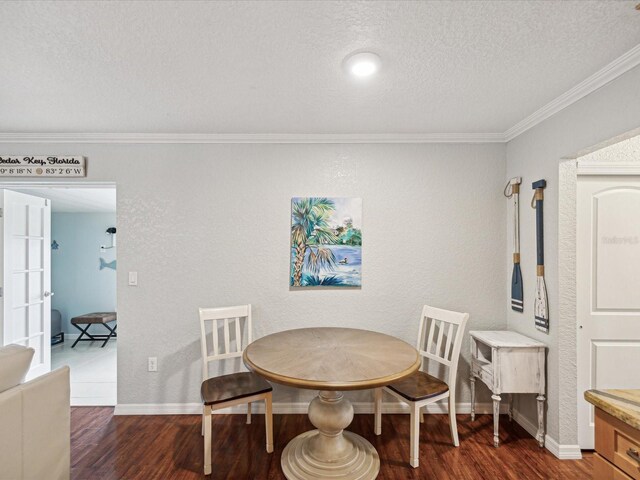 dining space featuring a textured ceiling, dark hardwood / wood-style flooring, and ornamental molding