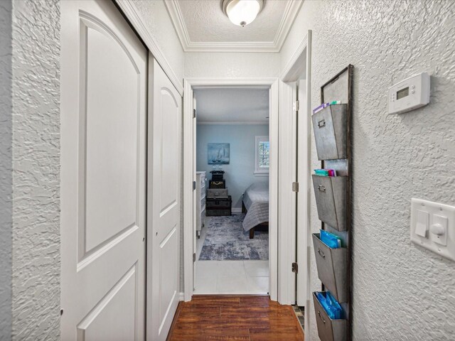 hall featuring dark wood-type flooring, a textured ceiling, and crown molding