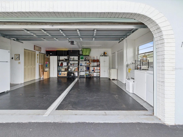 garage featuring washing machine and clothes dryer, a garage door opener, and white refrigerator