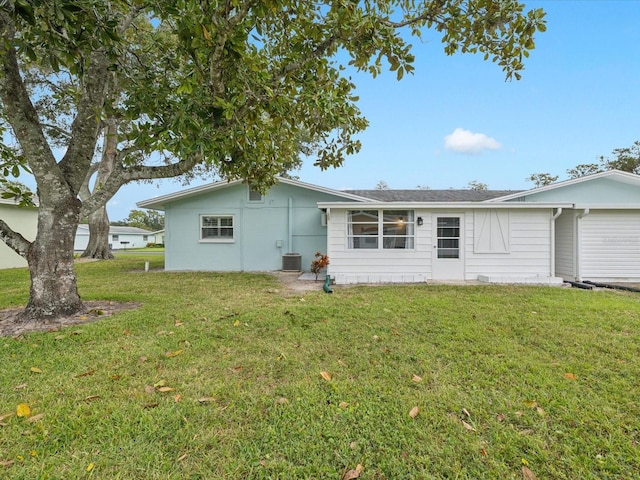 back of property featuring central air condition unit and a lawn