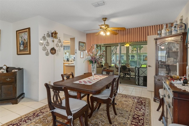 tiled dining space featuring a textured ceiling and ceiling fan