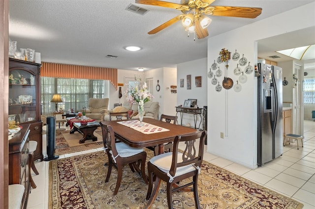 tiled dining room with ceiling fan and a textured ceiling