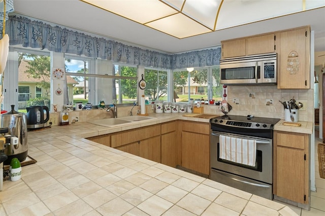 kitchen with tile counters, stainless steel appliances, sink, and backsplash