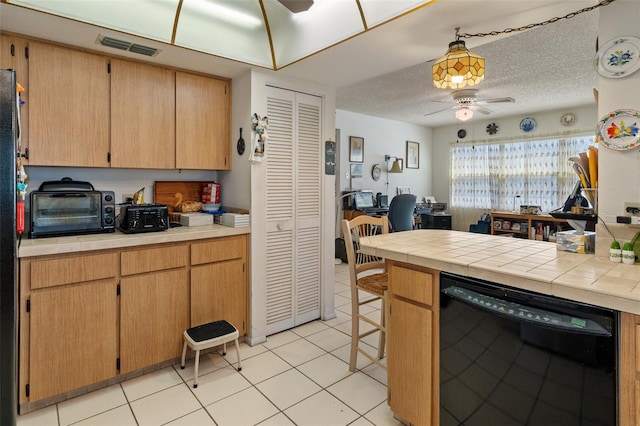 kitchen featuring ceiling fan, a textured ceiling, light tile patterned floors, and dishwasher