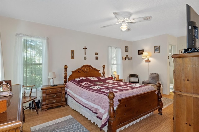 bedroom featuring ceiling fan, multiple windows, and light hardwood / wood-style floors