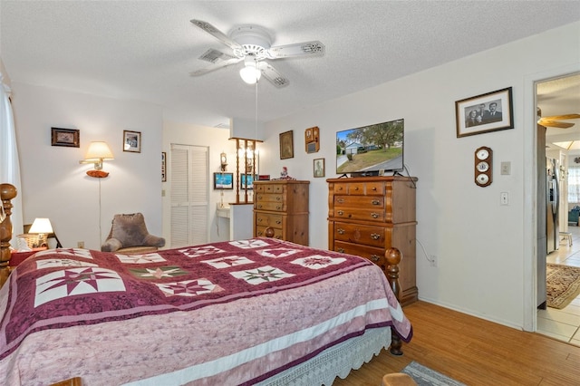 bedroom featuring a closet, a textured ceiling, stainless steel refrigerator, hardwood / wood-style flooring, and ceiling fan