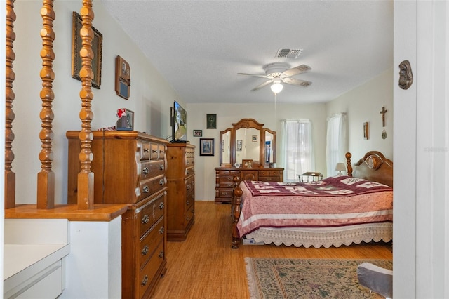 bedroom featuring light hardwood / wood-style floors, ceiling fan, and a textured ceiling