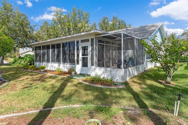 rear view of property with a lawn and a sunroom