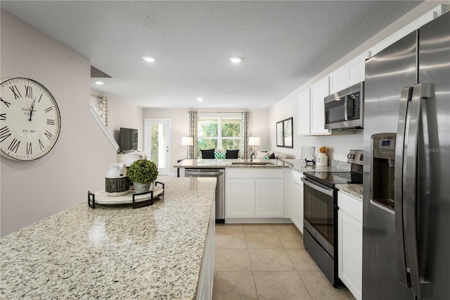 kitchen featuring stainless steel appliances, white cabinets, a textured ceiling, sink, and light stone countertops