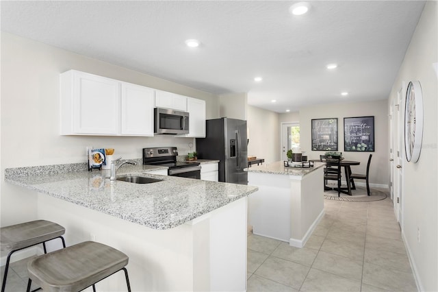 kitchen featuring a kitchen island, appliances with stainless steel finishes, light stone countertops, sink, and kitchen peninsula