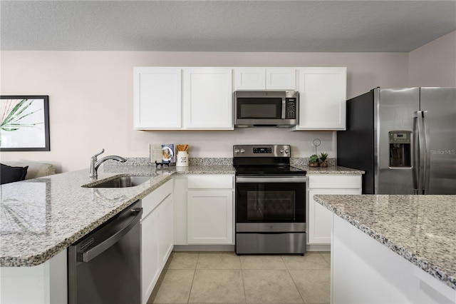 kitchen featuring stainless steel appliances, white cabinetry, sink, light stone counters, and light tile patterned floors