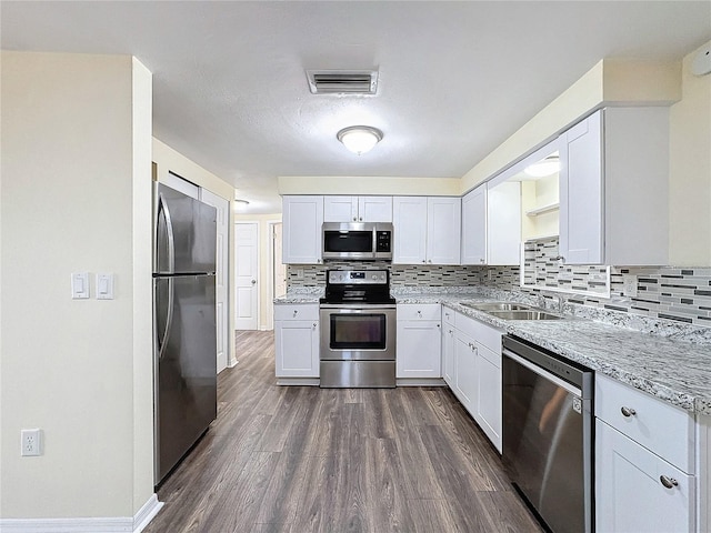 kitchen featuring sink, dark hardwood / wood-style floors, light stone countertops, white cabinetry, and appliances with stainless steel finishes