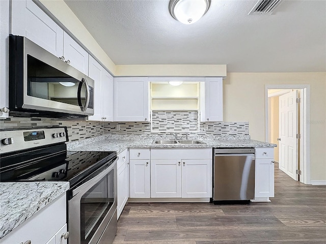 kitchen featuring stainless steel appliances, dark hardwood / wood-style floors, decorative backsplash, sink, and white cabinets