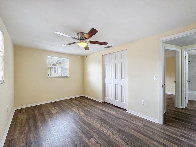 unfurnished bedroom with dark wood-type flooring, ceiling fan, and a closet