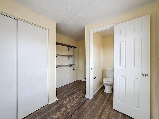 bathroom featuring toilet, wood-type flooring, and a textured ceiling