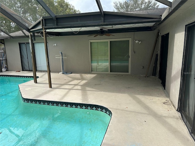 view of swimming pool featuring glass enclosure, a patio, and ceiling fan