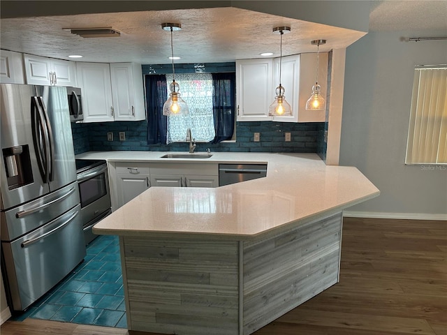 kitchen featuring dark hardwood / wood-style flooring, white cabinets, hanging light fixtures, sink, and appliances with stainless steel finishes