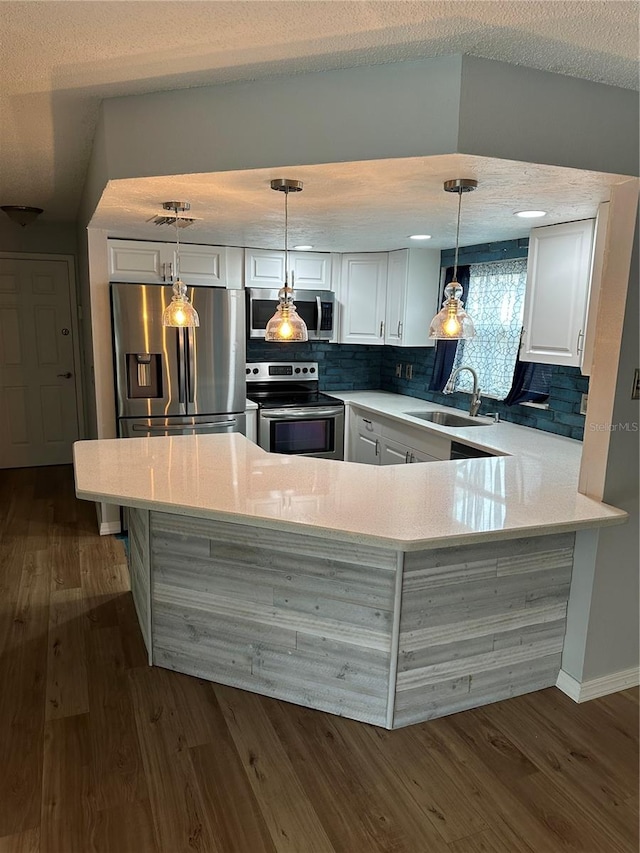 kitchen featuring white cabinets, appliances with stainless steel finishes, sink, and hanging light fixtures